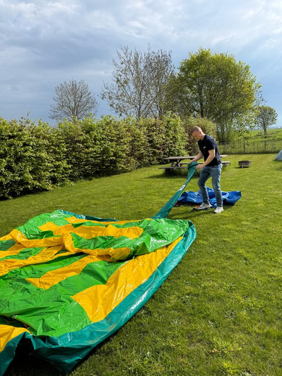 BounceMasters bouwt een groen geel springkussen op in een tuin